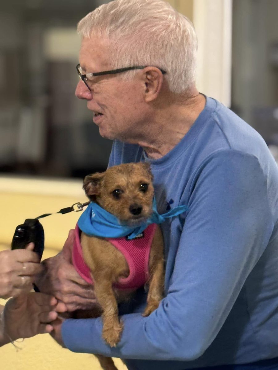 Therapy dog cuddling with a senior resident at Twin Creeks