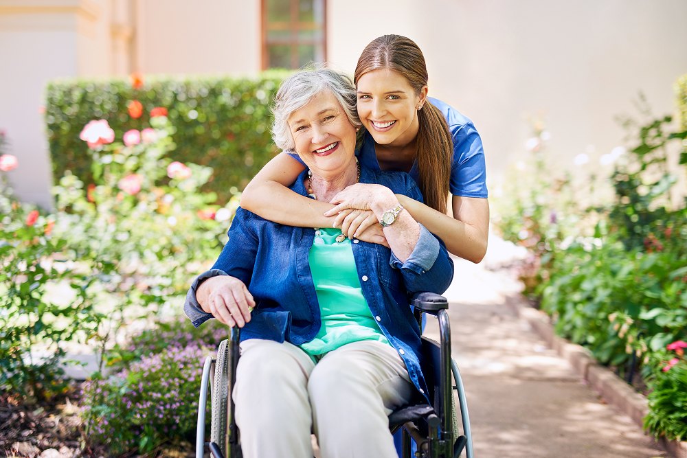 senior in wheel chair being hugged by her mom at an assisted living community. They are both smiling