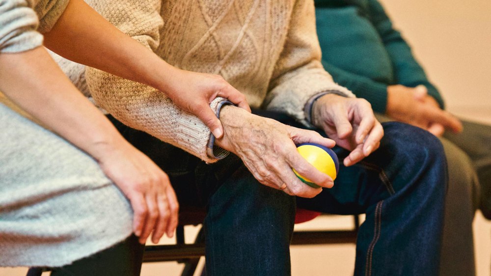 Gently holding the hand of an elderly parent as they discuss options and preferences for living at an assisted living facility.