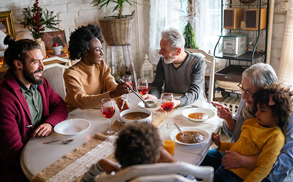 Happy multiethnic multigeneration family having fun together around kitchen table. People holiday food love happiness concept